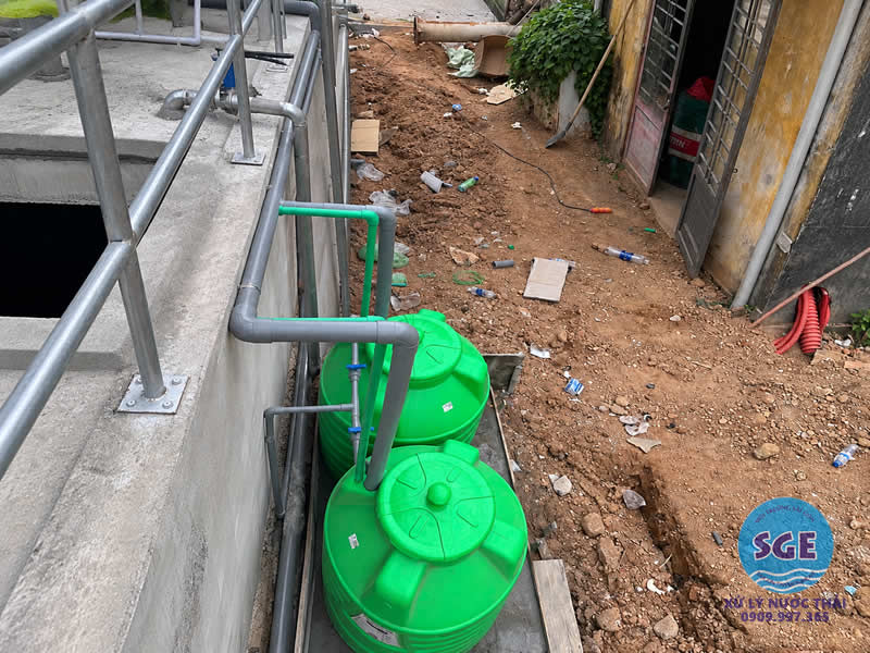 Hai bồn nhựa màu xanh kết nối đường ống trong hệ thống xử lý nước thải